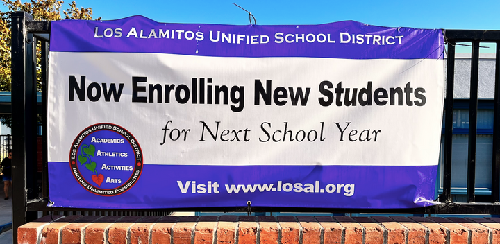 A banner announcing enrollment for the Los Alamitos Unified School District hangs outside McGaugh Elementary school in Seal B