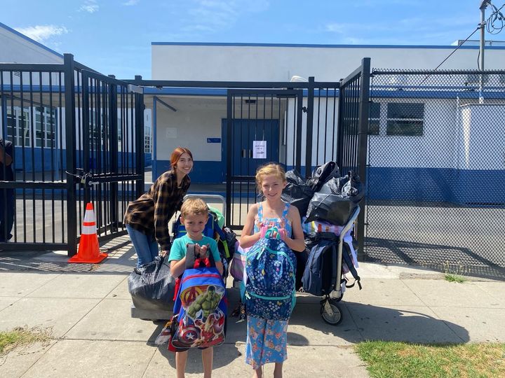Siblings Josie and Davin Gardner help deliver backpacks to Oak Street School's community liaison, Karlene Caro. The backpacks