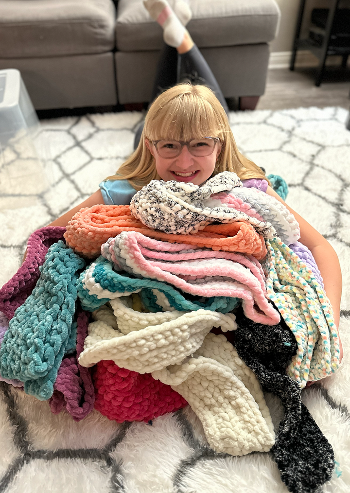McAuliffe Middle School student Alyssa Wiitanen holds the many scarves she's made to donate to a hospice in O.C. as one of he