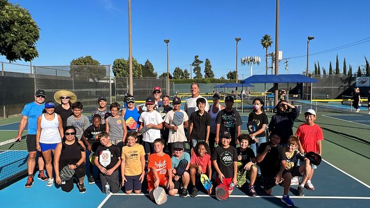 Players from McAuliffe Middle School's Pickleball Club pose with members of the Seal Beach Pickleball Association after a les