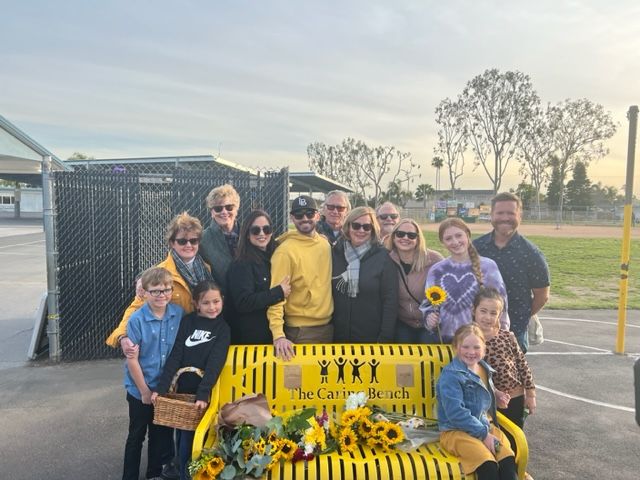 The family of Cari Crevda McQuiston, a beloved McGaugh Elementary School teacher who passed away in 2021, poses around the be