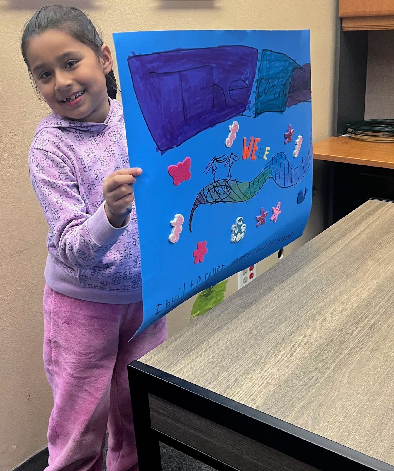 A Girls in STEM participant from the fall session displays her poster on the roller coaster experiment. Photo by Sarah Saadeh.